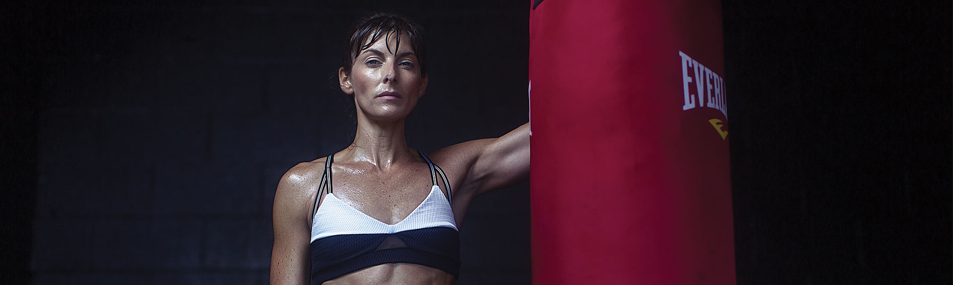 A woman in black and white bra holding a punching bag.